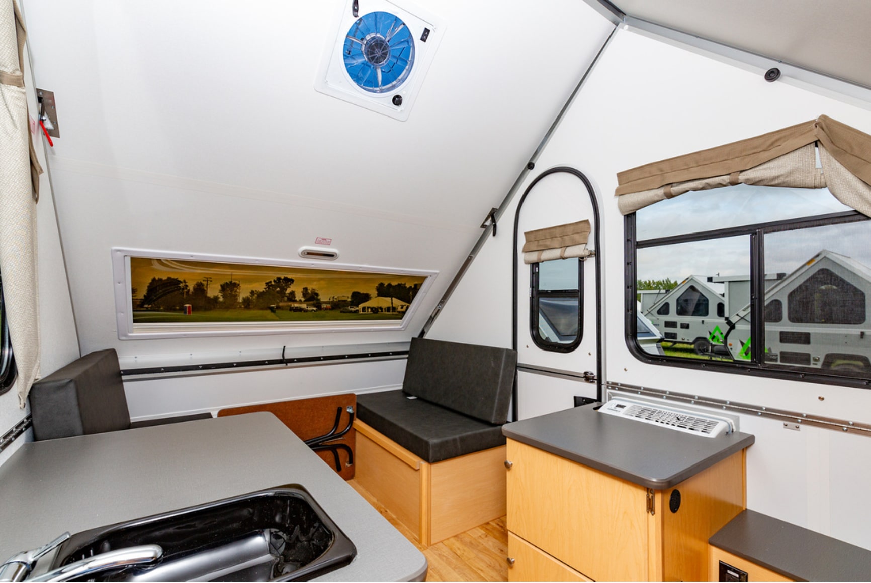 The interior of an rv with a sink and a window.
