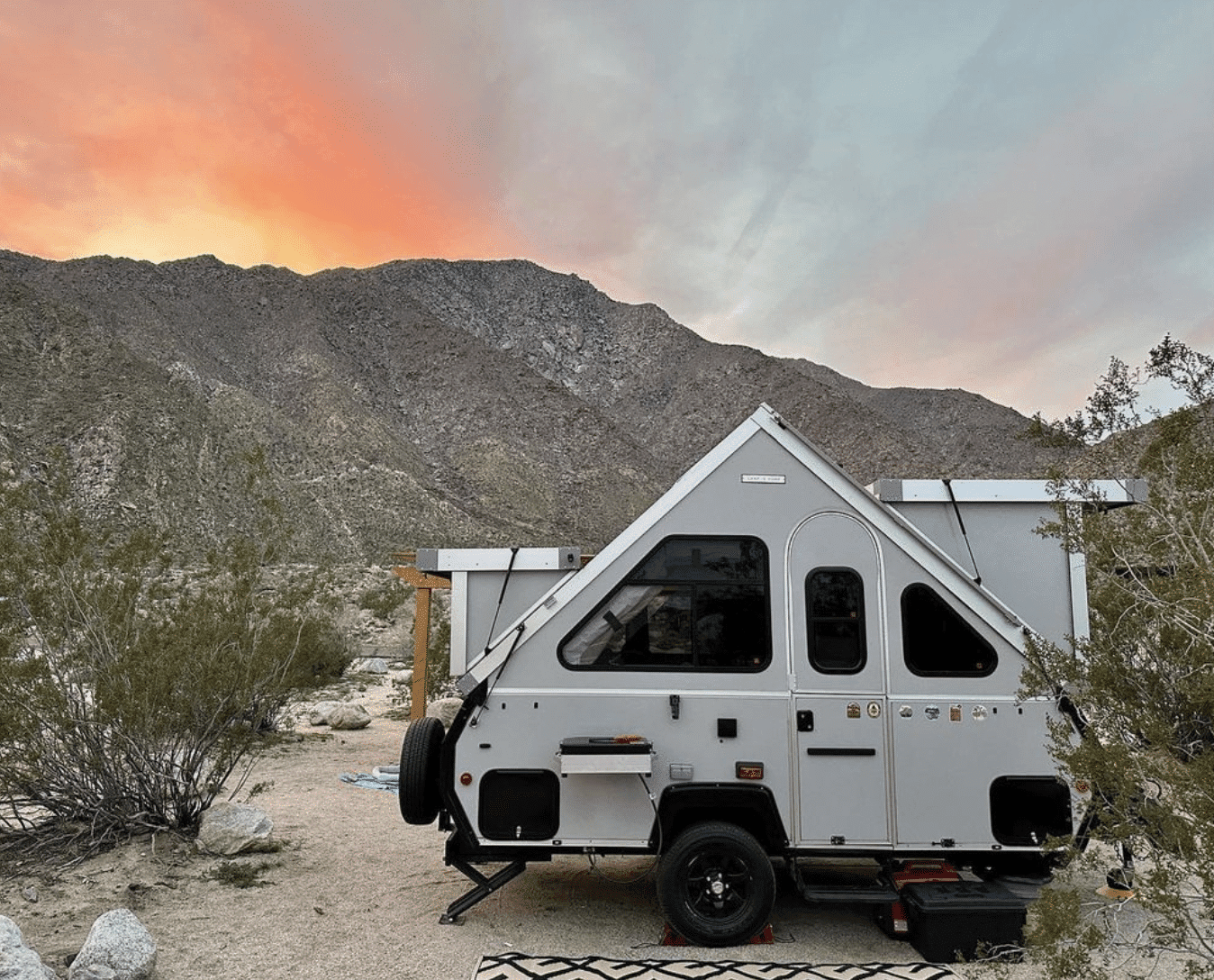 A white camper trailer parked in the desert.