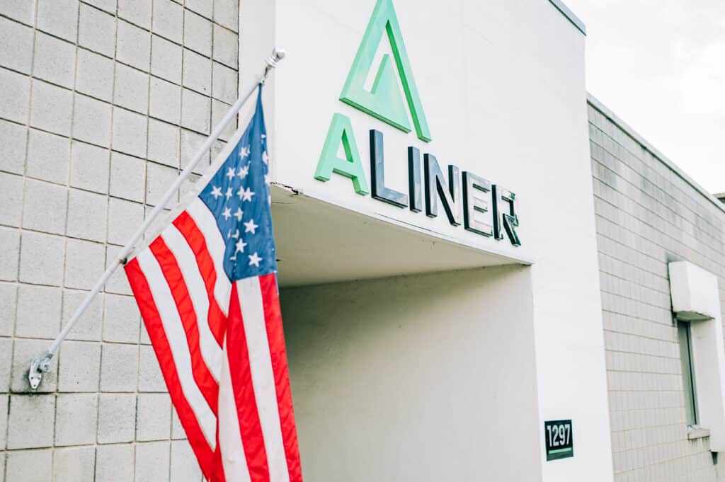 Aliner Manufacturing plant exterior with logo next to American flag.