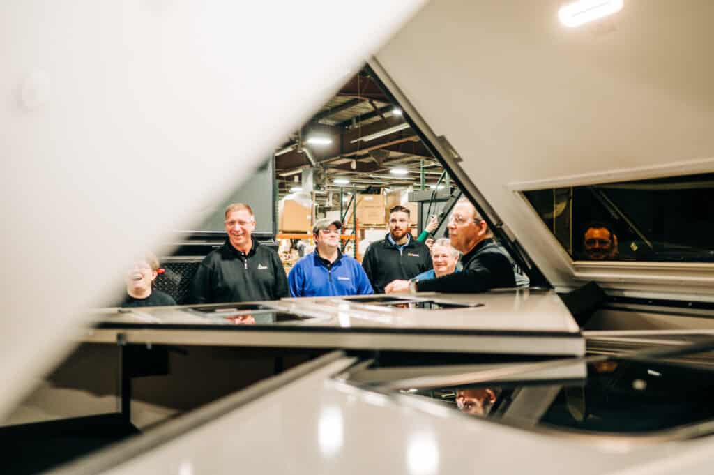 A group of men standing around in front of a mirror.