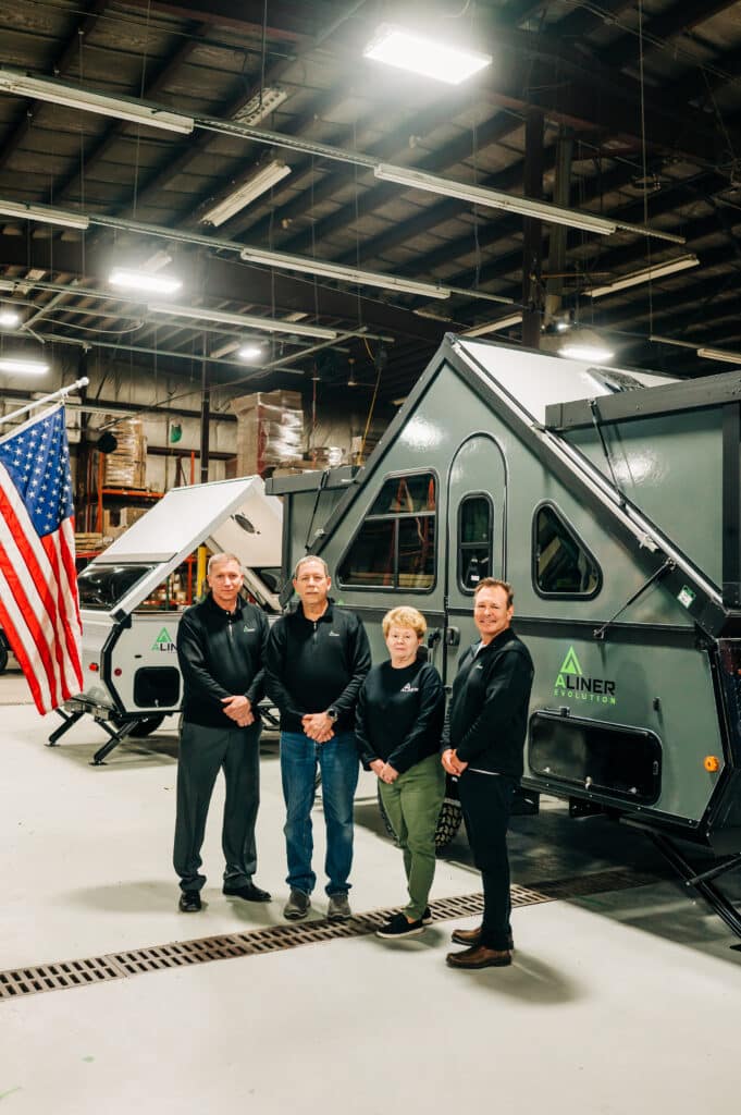 Three people standing in front of a trailer.