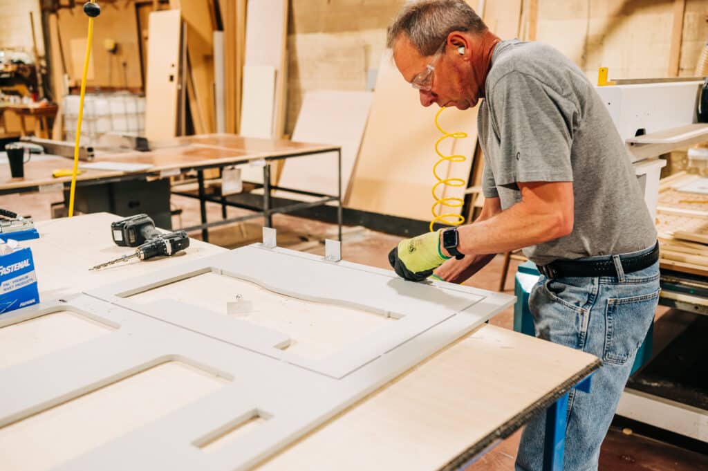 A man working on a cabinet in a workshop.