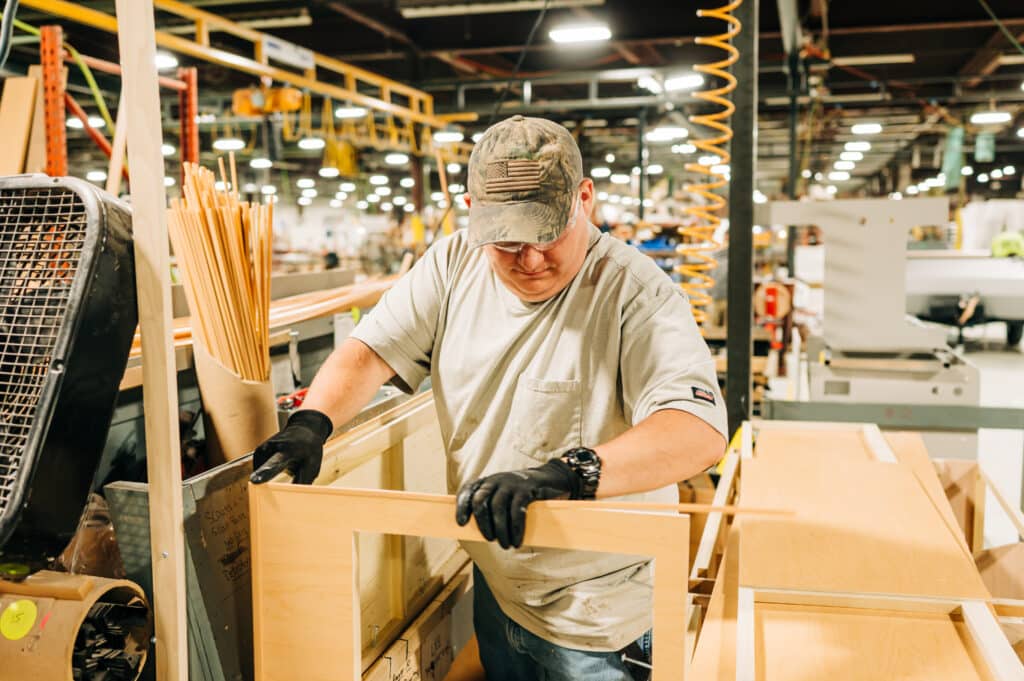 A man working in a factory with many wooden boards.