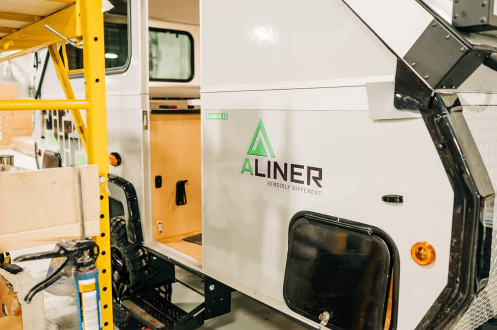 A white truck with the door open and the logo of aliner.