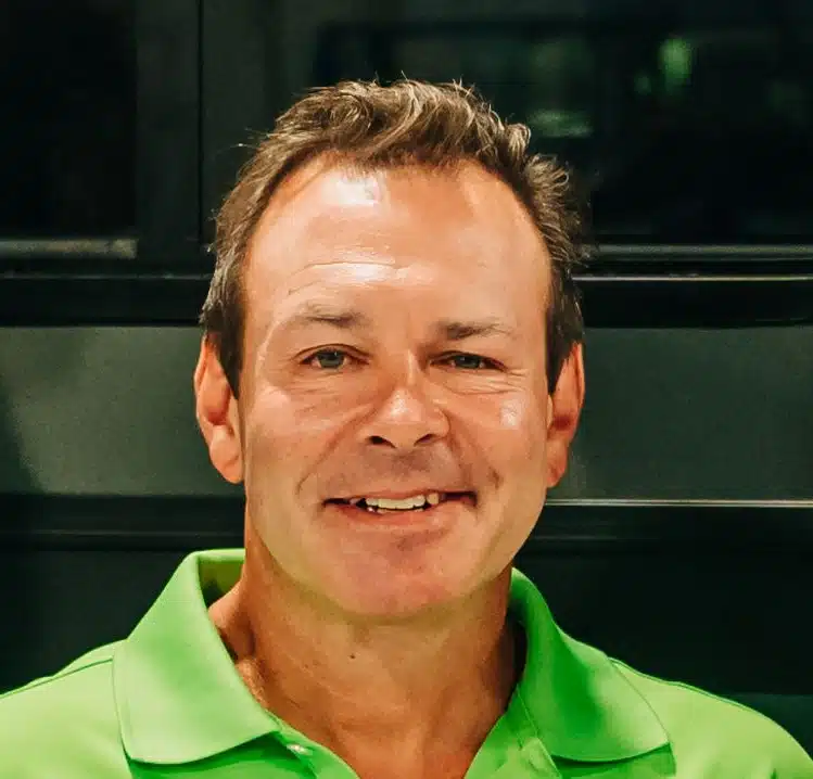 A smiling man wearing a green polo shirt celebrating an Aliner Anniversary.