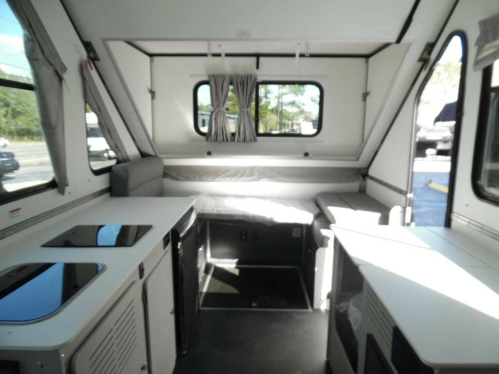 Interior of a compact rv featuring a bed, storage space, and a kitchenette.