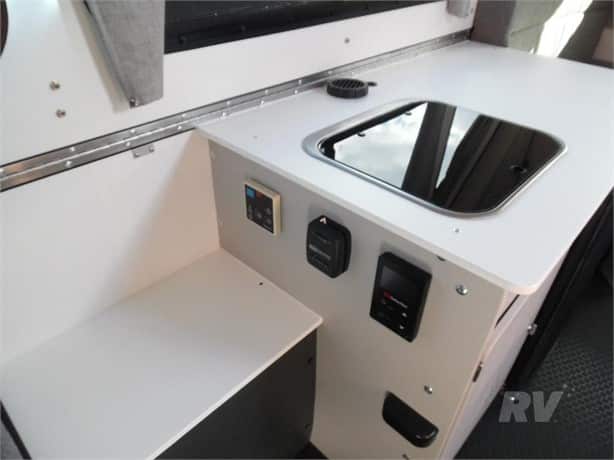 Interior view of a compact rv kitchenette with modern appliances and minimalist design.