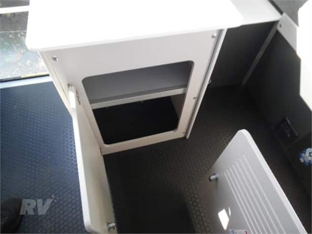 A compact rv interior featuring a small storage compartment and a textured floor.