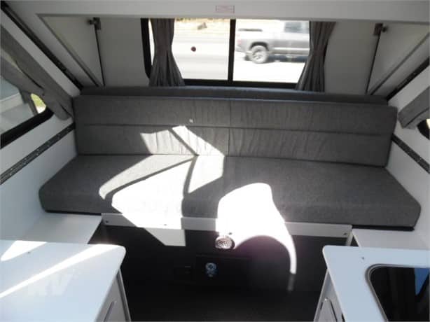 Interior of a recreational vehicle (rv) featuring a bench seat and window with sunlight casting a shadow.