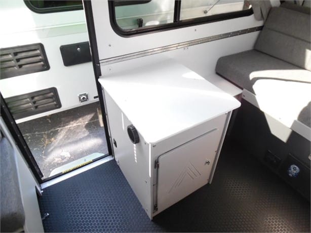 Interior of a vehicle showing a metal cabinet next to a seat.