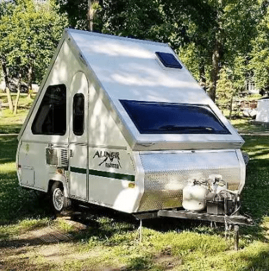 A small camper trailer parked in a park.